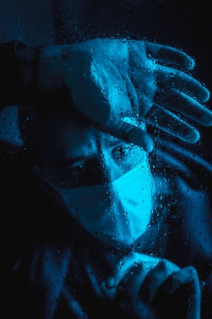 A guy behind a glass with rain droplets on it. Blue Colour Graded